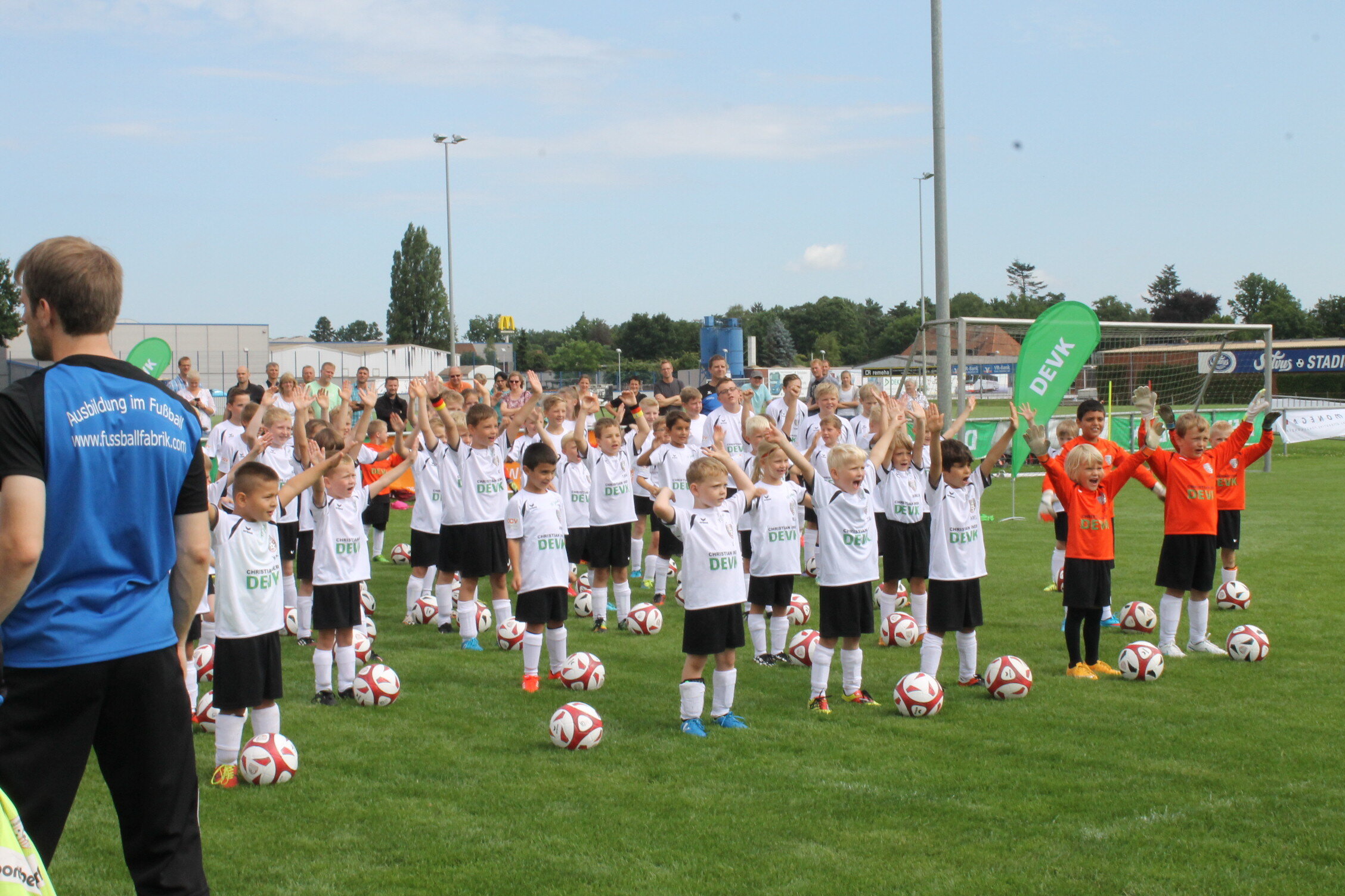 Bild von vielen Kindern auf einem Fußballplatz, die beim Fußballcamp mit Ingo Anderbrügge Spaß haben.