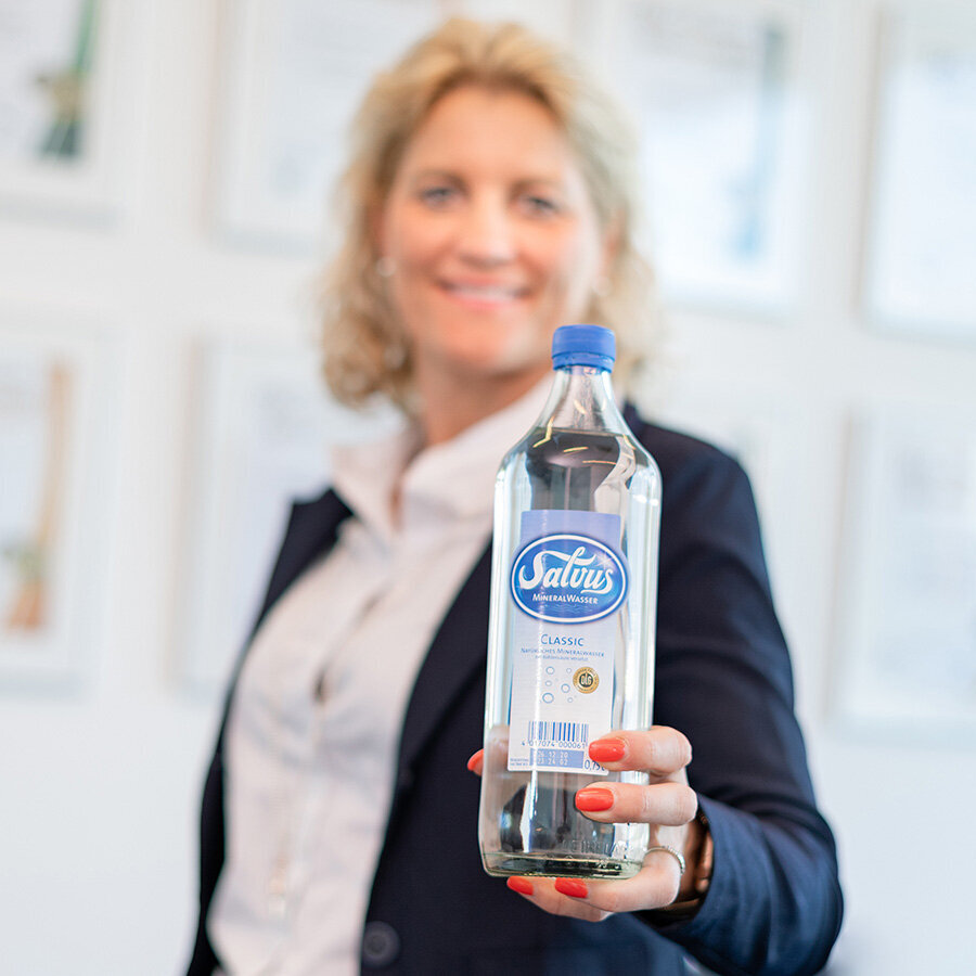 Bild von Heike Schürkötter, wie sie eine Flasche Salvus Classic Mineralwasser in die Kamera hält.