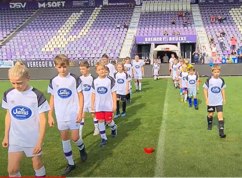 Die Teilnehmer vom Vfl-Kindertrainingtag laufen ins Stadion der Bremer Brücke ein.